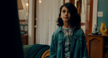 Movie still from “There's Something Wrong with the Children” (2023), directed by Roxanne Benjamin – A young girl is standing in front of a couch; Close Up shot, Over the shoulder angle