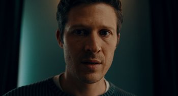 Movie still from “There's Something Wrong with the Children” (2023), directed by Roxanne Benjamin – A man's face in a sweater; Close Up shot, Low angle