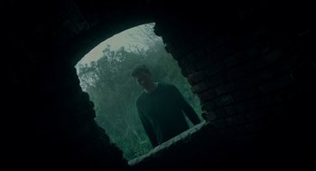 Movie still from “There's Something Wrong with the Children” (2023), directed by Roxanne Benjamin – A man standing in front of a brick wall; Wide shot, Low angle