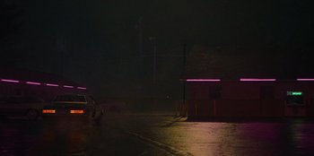 Movie still from “They Cloned Tyrone” (2023), directed by Juel Taylor – A car parked on the side of the road at night; Extreme Wide shot, Low angle