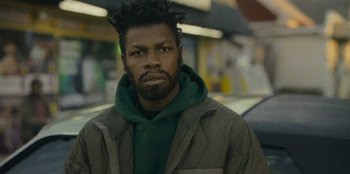 Movie still from “They Cloned Tyrone” (2023), directed by Juel Taylor – A person wearing a jacket; Close Up shot, Low angle