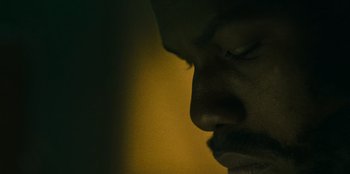 Movie still from “They Cloned Tyrone” (2023), directed by Juel Taylor – A man's face in the dark; Extreme Close Up shot, Overhead angle