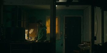 Movie still from “They Cloned Tyrone” (2023), directed by Juel Taylor – A person standing in a room with a light on; Medium shot, Low angle