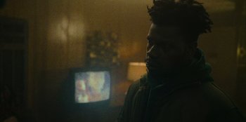 Movie still from “They Cloned Tyrone” (2023), directed by Juel Taylor – A man standing in front of a tv in a living room; Close Up shot, Low angle