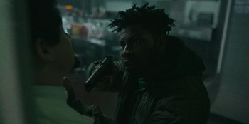 Movie still from “They Cloned Tyrone” (2023), directed by Juel Taylor – A man holding a gun in his hand; Close Up shot, Over the shoulder angle