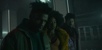 Movie still from “They Cloned Tyrone” (2023), directed by Juel Taylor – A group of people standing next to each other in a room; Medium shot, Low angle