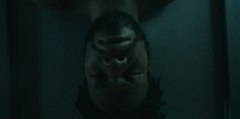 Movie still from “They Cloned Tyrone” (2023), directed by Juel Taylor – A person with their eyes closed in a dark room; Extreme Close Up shot, Overhead angle