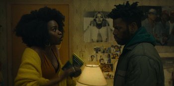 Movie still from “They Cloned Tyrone” (2023), directed by Juel Taylor – Two people standing next to each other in front of a lamp; Medium shot, Over the shoulder angle