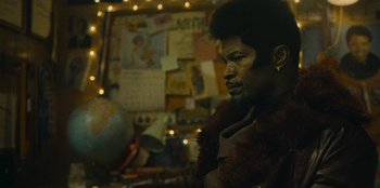 Movie still from “They Cloned Tyrone” (2023), directed by Juel Taylor – A man in a fur coat looking to his left; Close Up shot, Over the shoulder angle