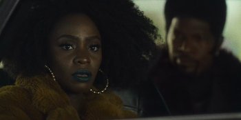Movie still from “They Cloned Tyrone” (2023), directed by Juel Taylor – A black woman with blue eyes looking at the camera; Close Up shot, Over the shoulder angle