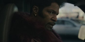 Movie still from “They Cloned Tyrone” (2023), directed by Juel Taylor – A person wearing a jacket; Close Up shot, Over the shoulder angle