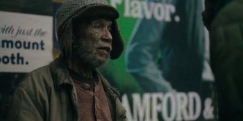 Movie still from “They Cloned Tyrone” (2023), directed by Juel Taylor – An old man wearing a hat is looking at the camera; Close Up shot, Low angle