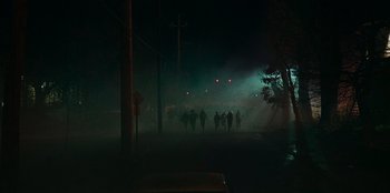 Movie still from “They Cloned Tyrone” (2023), directed by Juel Taylor – A group of people walking down a street at night; Extreme Wide shot, High angle