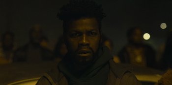 Movie still from “They Cloned Tyrone” (2023), directed by Juel Taylor – A person wearing a jacket; Close Up shot, Low angle