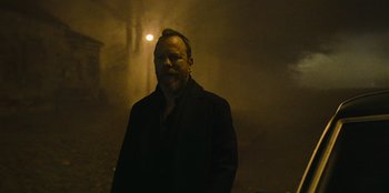 Movie still from “They Cloned Tyrone” (2023), directed by Juel Taylor – A man standing in the dark in front of a street light; Medium shot, Low angle