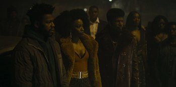 Movie still from “They Cloned Tyrone” (2023), directed by Juel Taylor – A group of people standing next to each other on a street; Medium shot, Low angle
