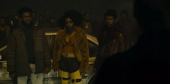 Movie still from “They Cloned Tyrone” (2023), directed by Juel Taylor – A group of people standing next to each other in front of a car; Medium shot, Low angle