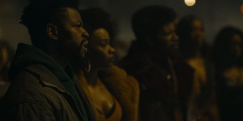Movie still from “They Cloned Tyrone” (2023), directed by Juel Taylor – A group of people standing next to each other in a room; Close Up shot, Low angle