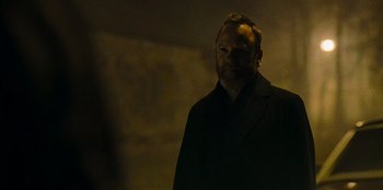 Movie still from “They Cloned Tyrone” (2023), directed by Juel Taylor – A man standing in a dark room with his eyes closed; Close Up shot, Over the shoulder angle