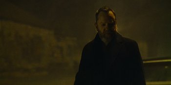 Movie still from “They Cloned Tyrone” (2023), directed by Juel Taylor – A man in a black jacket standing in the dark; Close Up shot, Low angle