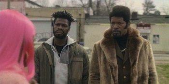 Movie still from “They Cloned Tyrone” (2023), directed by Juel Taylor – Two men standing next to each other on the street; Close Up shot, Low angle
