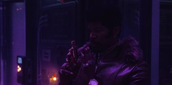 Movie still from “They Cloned Tyrone” (2023), directed by Juel Taylor – A man holding a gun in his hand; Close Up shot, Low angle