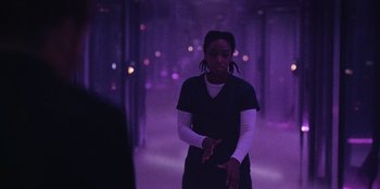 Movie still from “They Cloned Tyrone” (2023), directed by Juel Taylor – A person standing in a room with purple lights; Medium shot, Over the shoulder angle