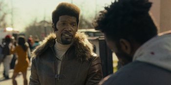 Movie still from “They Cloned Tyrone” (2023), directed by Juel Taylor – A man in a brown jacket talking to another man in a brown jacket; Close Up shot, Over the shoulder angle