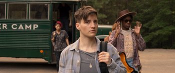 Movie still from “They/Them” (2022), directed by John Logan – A young man with a beard is holding a backpack; Close Up shot, Over the shoulder angle