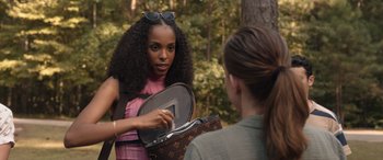 Movie still from “They/Them” (2022), directed by John Logan – A woman is holding a purse while talking to another woman; Medium shot, Over the shoulder angle