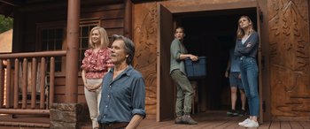 Movie still from “They/Them” (2022), directed by John Logan – A man and a woman standing in front of a wooden door; Wide shot, Low angle