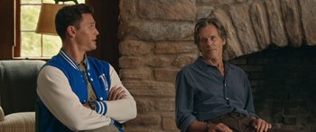 Movie still from “They/Them” (2022), directed by John Logan – Two men sitting next to each other in front of a brick wall; Medium shot, Over the shoulder angle