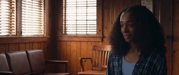 Movie still from “They/Them” (2022), directed by John Logan – A young woman with long curly hair in a room with wood paneled walls; Close Up shot, Over the shoulder angle