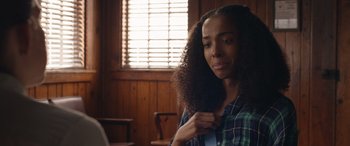 Movie still from “They/Them” (2022), directed by John Logan – A young woman brushing her hair in a room with wooden paneling; Close Up shot, Over the shoulder angle