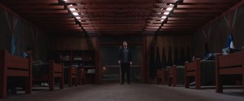 Movie still from “They/Them” (2022), directed by John Logan – A man standing in front of an open door; Wide shot, Low angle