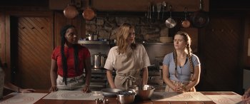 Movie still from “They/Them” (2022), directed by John Logan – Three people standing in a kitchen preparing a meal; Medium shot, Low angle