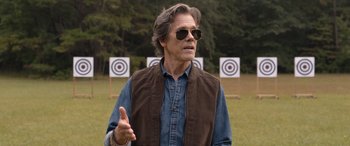 Movie still from “They/Them” (2022), directed by John Logan – A man wearing sunglasses standing in front of targets; Close Up shot, Over the shoulder angle