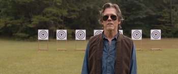 Movie still from “They/Them” (2022), directed by John Logan – A man standing in front of targets in a field; Close Up shot, Over the shoulder angle