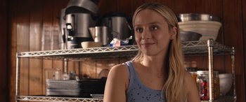 Movie still from “They/Them” (2022), directed by John Logan – A woman in a blue shirt in front of a shelf of pots and pans; Close Up shot, Over the shoulder angle