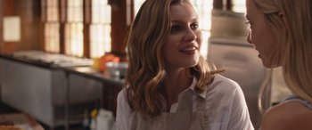 Movie still from “They/Them” (2022), directed by John Logan – A woman in an apron is smiling for the camera; Close Up shot, Over the shoulder angle