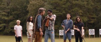 Movie still from “They/Them” (2022), directed by John Logan – A group of people standing in front of an archery target; Medium shot, Over the shoulder angle
