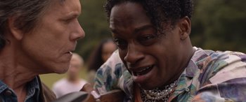 Movie still from “They/Them” (2022), directed by John Logan – A man with curly hair is smiling at another man; Close Up shot, Over the shoulder angle