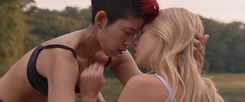 Movie still from “They/Them” (2022), directed by John Logan – A young man and a young woman are kissing in a field; Close Up shot, Over the shoulder angle