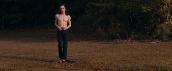 Movie still from “They/Them” (2022), directed by John Logan – A man standing in the grass with his hands on his hips; Medium shot, Low angle