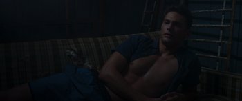 Movie still from “They/Them” (2022), directed by John Logan – A man laying on a couch in a dark room; Medium shot, High angle