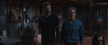 Movie still from “They/Them” (2022), directed by John Logan – A man and a man standing next to each other in a room; Medium shot, Over the shoulder angle