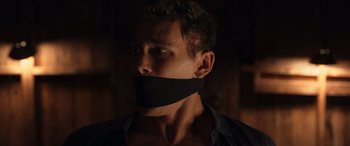 Movie still from “They/Them” (2022), directed by John Logan – A man with a mouth taped to his face; Close Up shot, Low angle