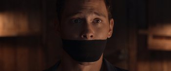 Movie still from “They/Them” (2022), directed by John Logan – A man with a black tape over his mouth; Close Up shot, Low angle