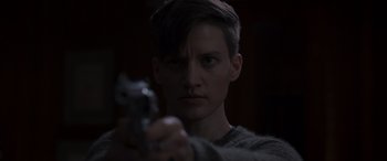 Movie still from “They/Them” (2022), directed by John Logan – A man holding a gun in a dark room; Close Up shot, Over the shoulder angle