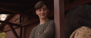 Movie still from “They/Them” (2022), directed by John Logan – A young man standing in front of a wooden wall; Close Up shot, Over the shoulder angle